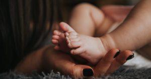 person holding baby s feet in selective focus photography